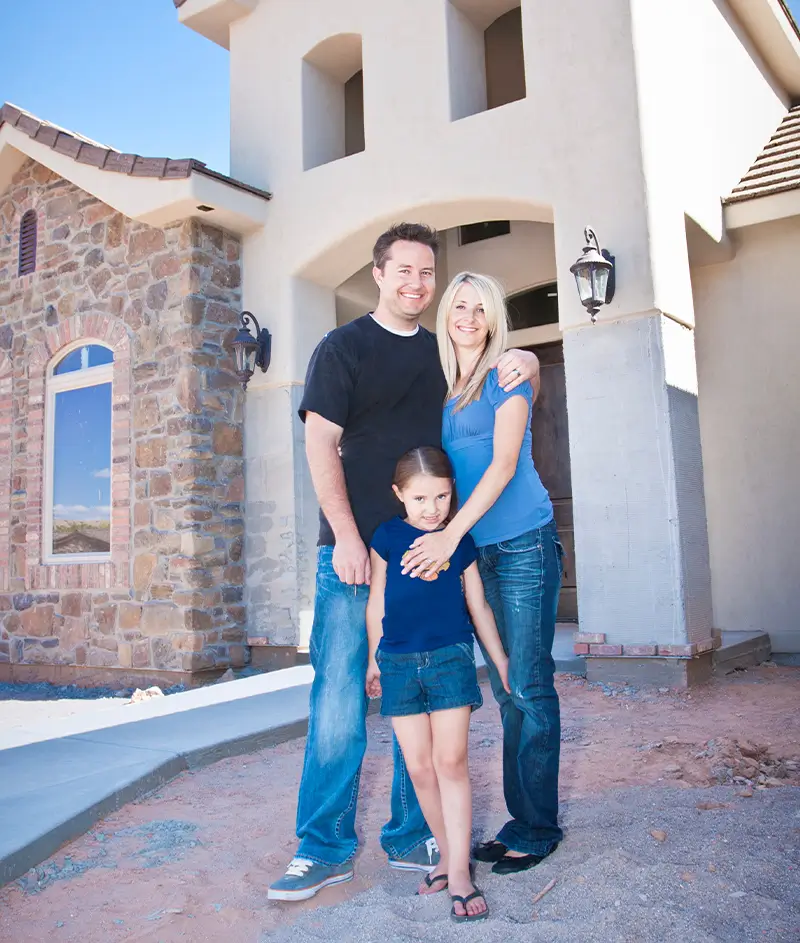 Mom, dad, and daughter standing in front of house smiling